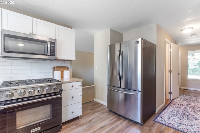 13503 NE 80th Cir, Vancouver, WA 98682 - kitchen with appliances with stainless steel finishes, white cabinets, light wood finished floors, and a textured ceiling