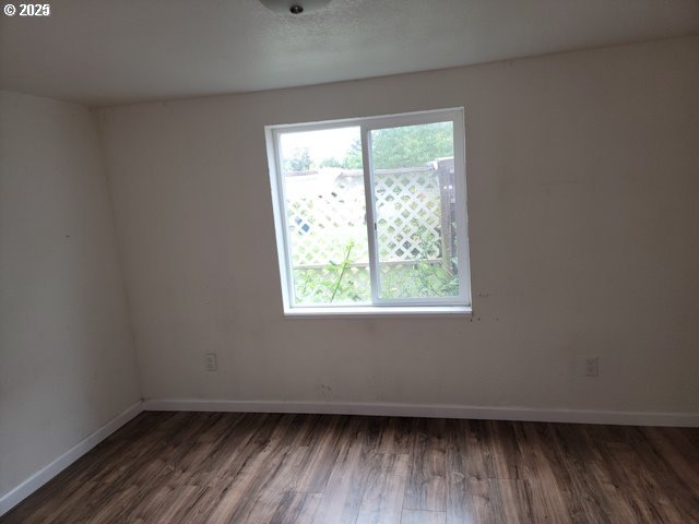 spare room featuring a textured ceiling, dark wood-type flooring, and baseboards