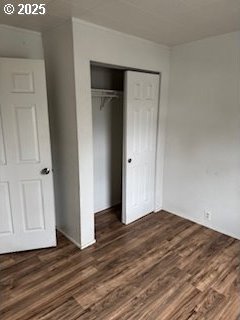 unfurnished bedroom with dark wood-style floors and a closet