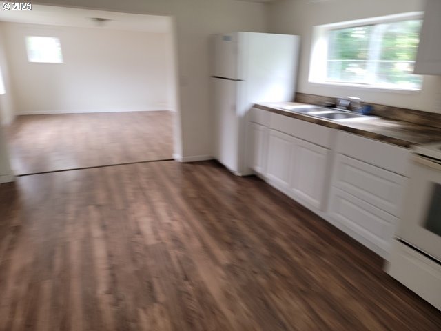 kitchen featuring dark countertops, white cabinets, a sink, white appliances, and under cabinet range hood