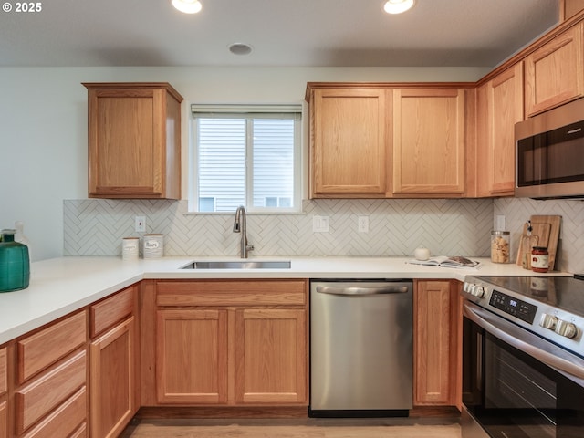kitchen featuring light countertops, a sink, appliances with stainless steel finishes, and tasteful backsplash