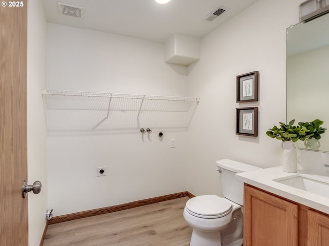 bathroom with toilet, visible vents, wood finished floors, and vanity