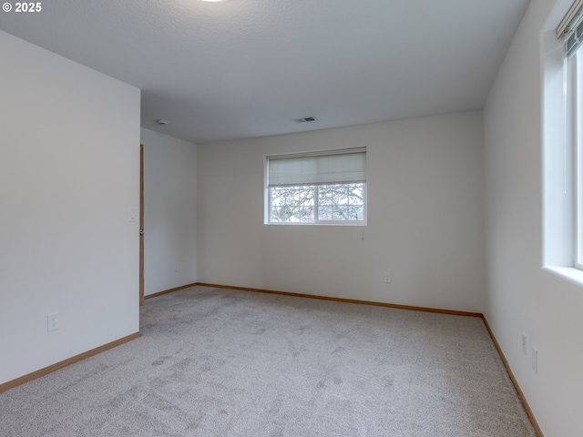 carpeted empty room featuring visible vents and baseboards