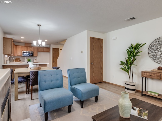 living room featuring an inviting chandelier, recessed lighting, baseboards, light wood-type flooring, and visible vents