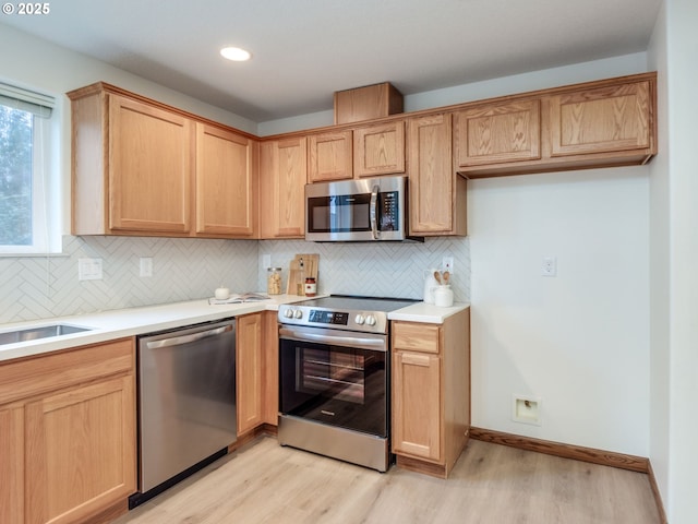 kitchen with light wood-style flooring, tasteful backsplash, light brown cabinets, and stainless steel appliances