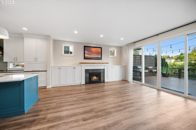 unfurnished living room featuring recessed lighting, light wood-style flooring, and a tile fireplace