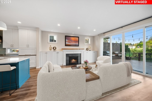 living room with light wood-type flooring, recessed lighting, and a tile fireplace