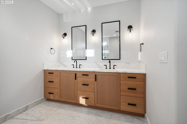 full bathroom featuring marble finish floors, baseboards, and double vanity