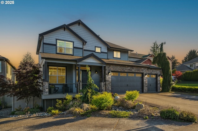 craftsman inspired home with a porch, driveway, stone siding, and a garage