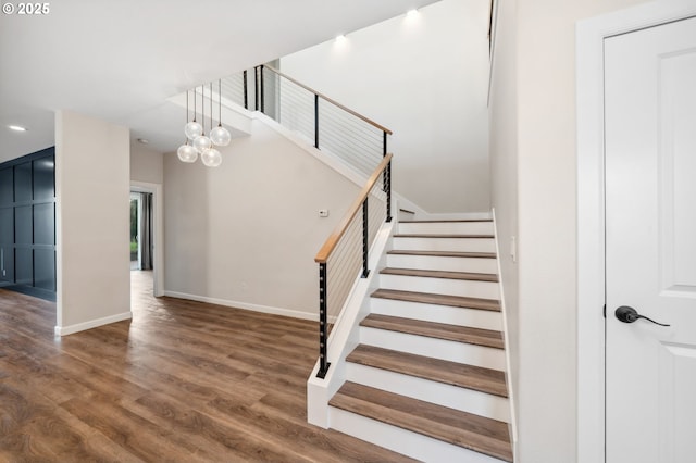 staircase featuring wood finished floors, baseboards, and recessed lighting