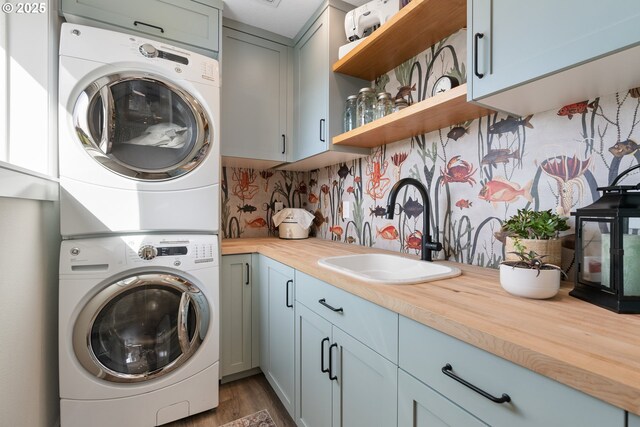 laundry room featuring stacked washer / dryer, dark wood-style floors, and cabinet space
