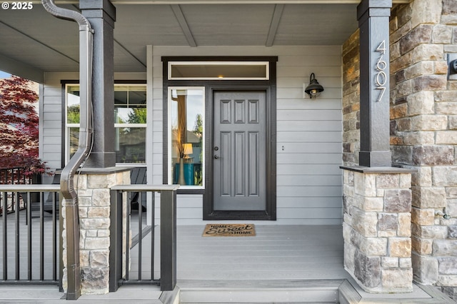 doorway to property with covered porch and stone siding