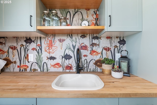 kitchen view of a sink, butcher block counters, and open shelves