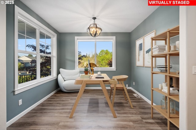 living area with a chandelier, wood finished floors, baseboards, and a desk