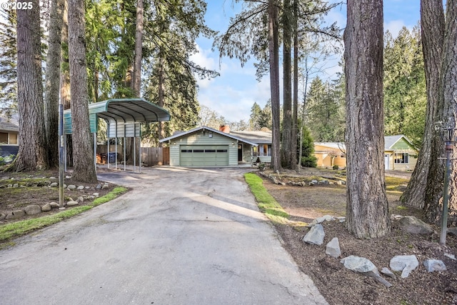 view of front of property featuring aphalt driveway, a chimney, a carport, fence, and a garage