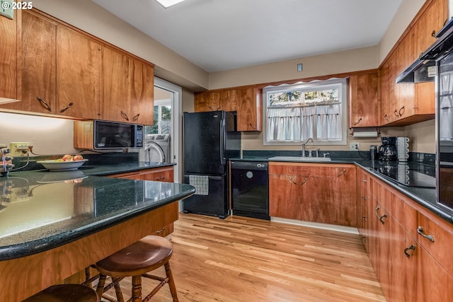 kitchen with washer / dryer, brown cabinets, a sink, and black appliances