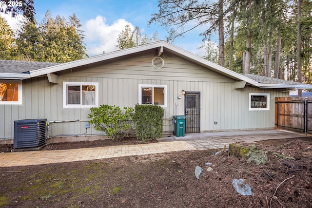 view of front of house with central air condition unit, a patio area, a shingled roof, and fence