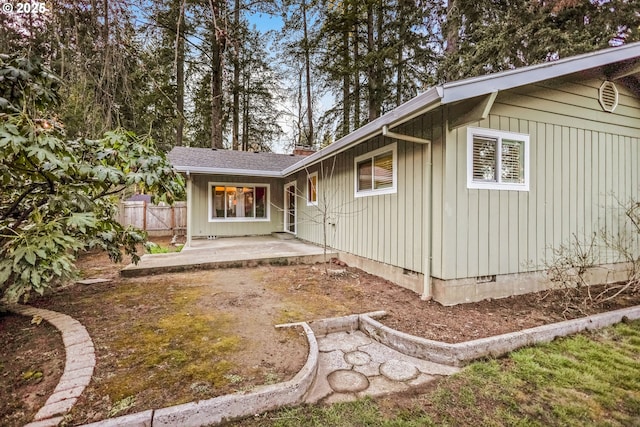 rear view of house with fence, roof with shingles, crawl space, board and batten siding, and a patio area