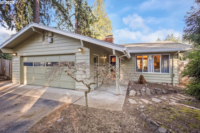 single story home featuring a garage, concrete driveway, fence, and a chimney