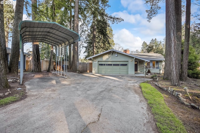 view of front of house with aphalt driveway, a garage, fence, a carport, and a chimney