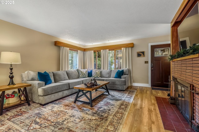 living room with a fireplace, a textured ceiling, baseboards, and wood finished floors