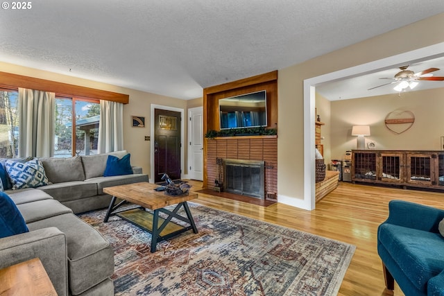 living area featuring a textured ceiling, a brick fireplace, and wood finished floors