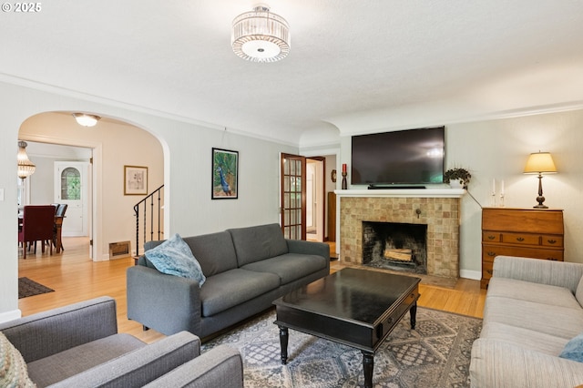 7150 SE 27th Ave, Portland, OR 97202 - living room featuring arched walkways, wood finished floors, a fireplace, ornamental molding, and stairway
