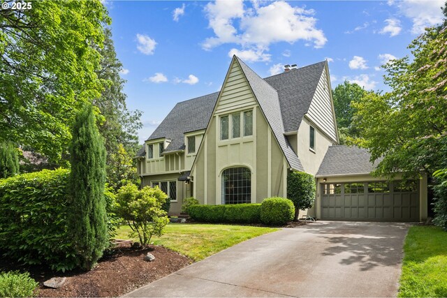 7150 SE 27th Ave, Portland, OR 97202 - tudor-style house featuring stucco siding, roof with shingles, a front yard, and driveway