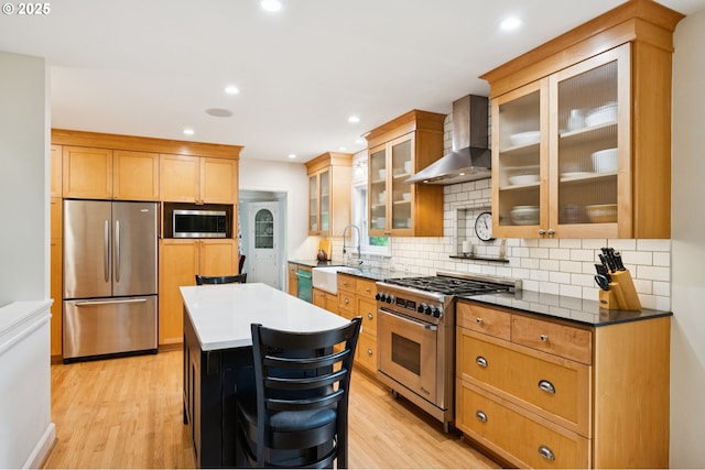 7150 SE 27th Ave, Portland, OR 97202 - kitchen featuring appliances with stainless steel finishes, wall chimney range hood, light wood-style flooring, tasteful backsplash, and recessed lighting