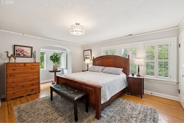 7150 SE 27th Ave, Portland, OR 97202 - bedroom with light wood-type flooring, ornamental molding, arched walkways, and a textured ceiling