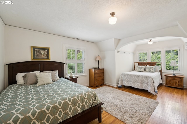7150 SE 27th Ave, Portland, OR 97202 - bedroom featuring multiple windows, arched walkways, hardwood / wood-style floors, and a textured ceiling
