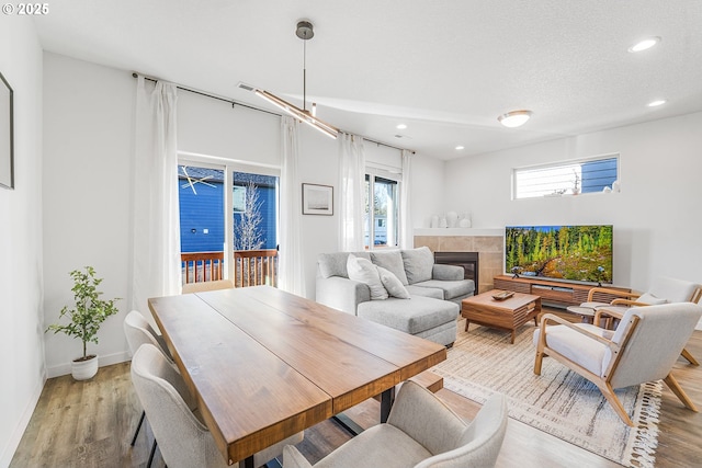 dining area with light wood-style floors, recessed lighting, baseboards, and a tile fireplace