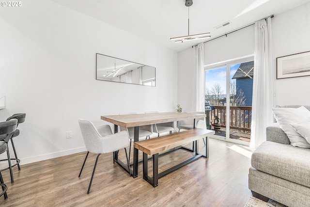 dining space featuring baseboards, visible vents, and light wood finished floors