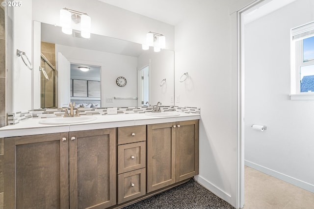 full bath featuring a shower with shower door, a sink, baseboards, and double vanity