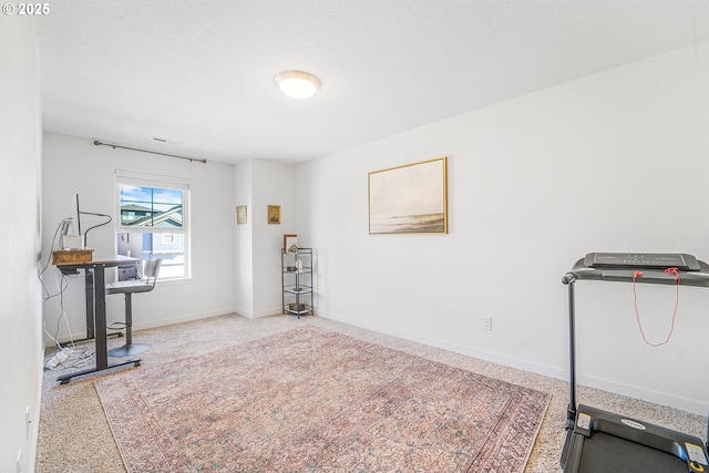 exercise area with a textured ceiling and baseboards