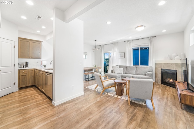 living area with recessed lighting, a fireplace, visible vents, and light wood-style floors