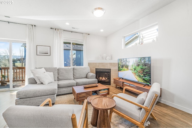 living room featuring plenty of natural light, a fireplace, baseboards, and wood finished floors