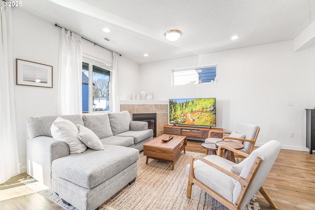 living area with a fireplace, visible vents, wood finished floors, and recessed lighting