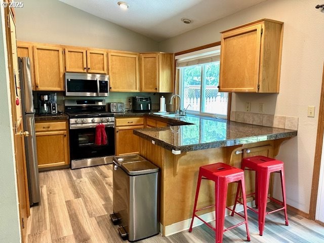 4120 NE 52nd St, Vancouver, WA 98661 - kitchen featuring appliances with stainless steel finishes, light wood-type flooring, a peninsula, vaulted ceiling, and a kitchen breakfast bar