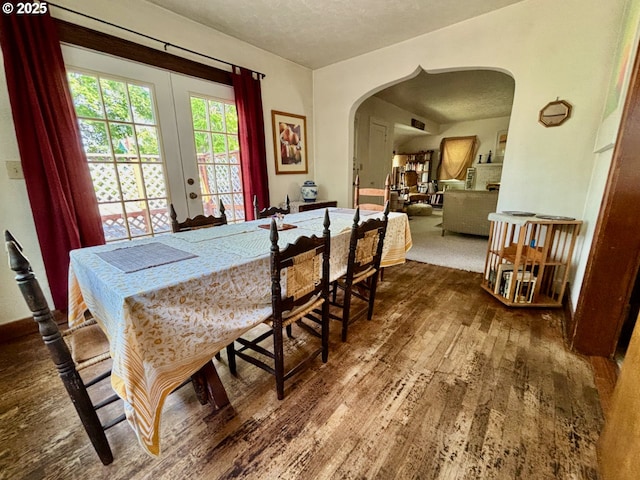991 Polk St, Eugene, OR 97402 - dining room featuring arched walkways, wood finished floors, a textured ceiling, and french doors
