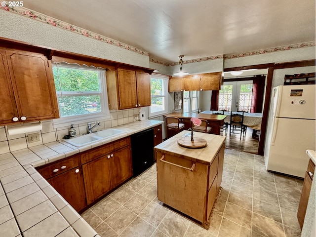 991 Polk St, Eugene, OR 97402 - kitchen with freestanding refrigerator, dishwasher, tile countertops, and brown cabinets