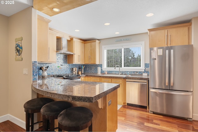 17460 Old Pacific Hwy, Rockaway Beach, OR 97136 - kitchen featuring stainless steel appliances, wall chimney range hood, a sink, tile countertops, and a peninsula
