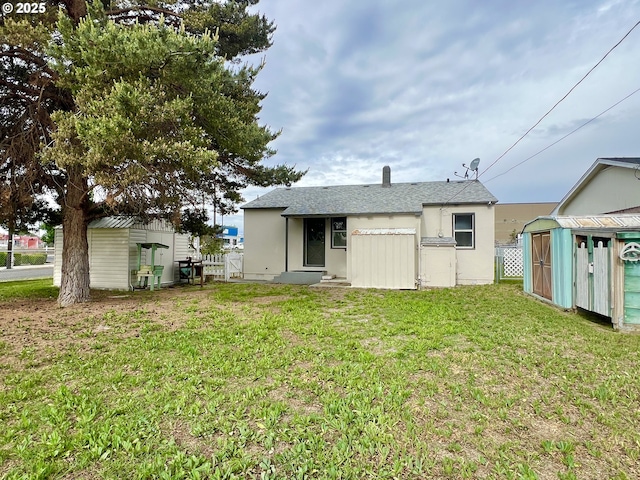 610 NE N St, Hermiston, OR 97838 - back of house with a shed, an outbuilding, stucco siding, and roof with shingles