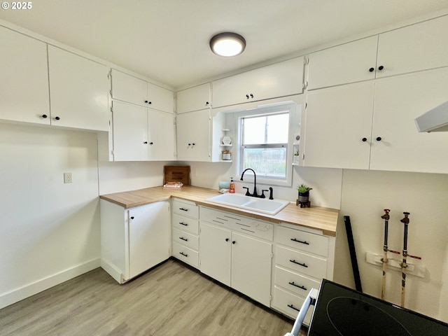 610 NE N St, Hermiston, OR 97838 - kitchen featuring a sink, light wood finished floors, baseboards, white cabinets, and wooden counters