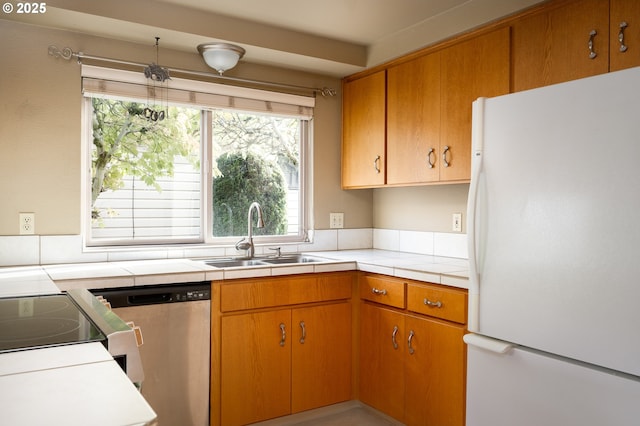 kitchen with dishwasher, white fridge, sink, range with electric stovetop, and tile countertops