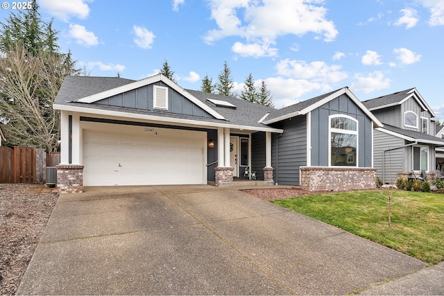 craftsman house with brick siding, an attached garage, central AC, fence, and driveway