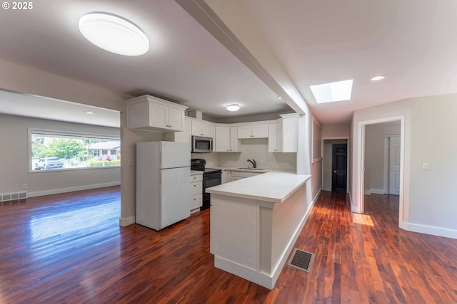 3826 SE 50th Ave, Portland, OR 97206 - kitchen featuring freestanding refrigerator, electric range, stainless steel microwave, a skylight, and a peninsula