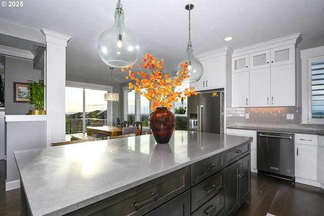 1936 NW Klickitat St, Camas, WA 98607 - kitchen featuring decorative backsplash, appliances with stainless steel finishes, white cabinetry, decorative light fixtures, and dark wood-style floors
