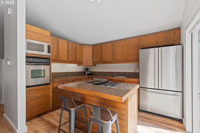 563 Fairway Dr, Gleneden Beach, OR 97388 - kitchen with stainless steel appliances, light wood-type flooring, and brown cabinetry