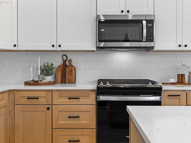 6719 NE 132nd St, Vancouver, WA 98686 - kitchen featuring stainless steel microwave, stove, white cabinetry, and decorative backsplash